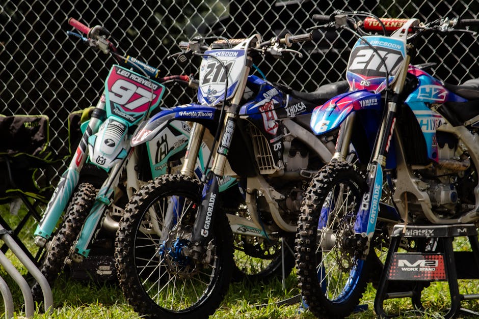 Vibrant motocross bikes parked outdoors in La Marquesa, showcasing colorful designs, ready for adventure.